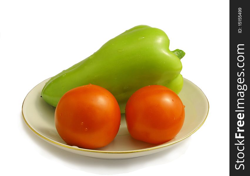 A light green bell peppers and two ripe red tomato on a porcelain dish and vegetables on white background. A light green bell peppers and two ripe red tomato on a porcelain dish and vegetables on white background