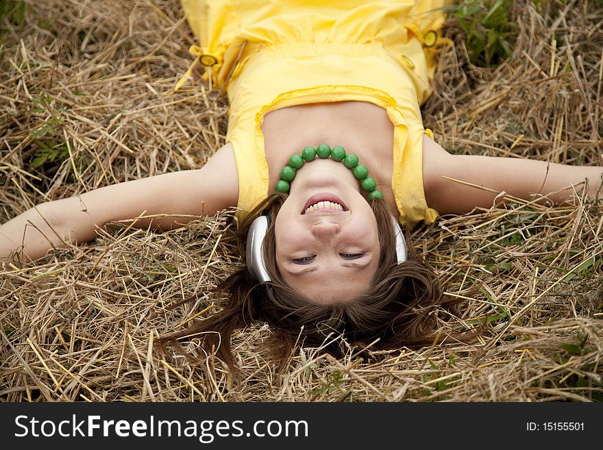 Young beautiful girl in yellow with headphones at field.