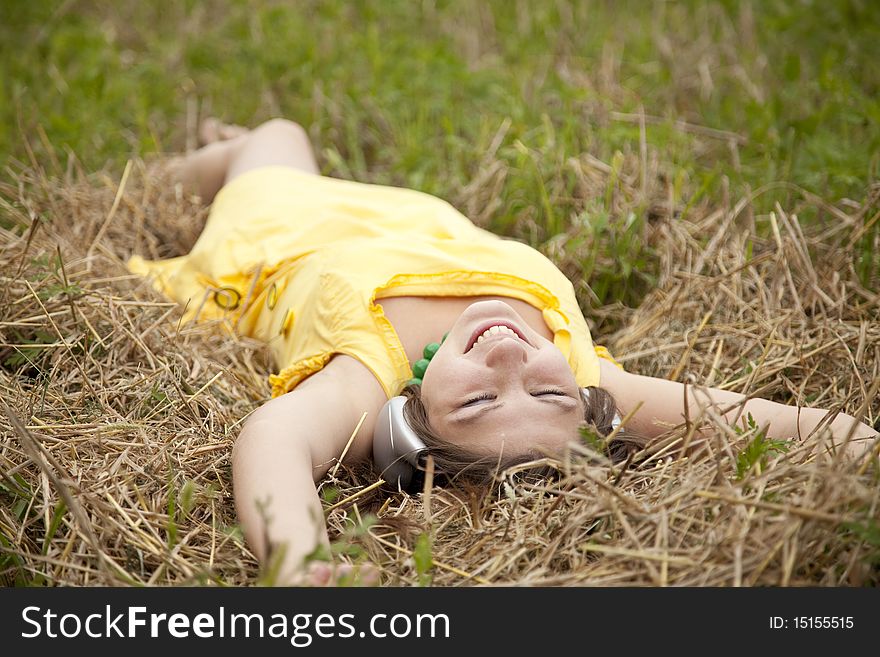 Young beautiful girl in yellow with headphones at field.