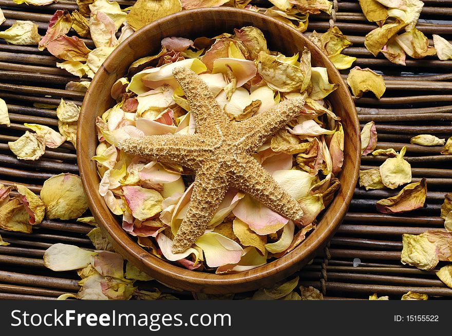 Bowl of orchid petals with starfish on bamboo mat. Bowl of orchid petals with starfish on bamboo mat