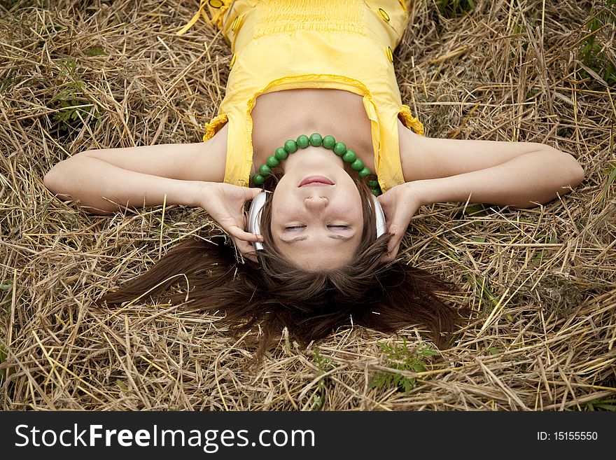 Young beautiful girl in yellow with headphones at field.