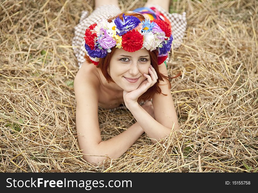 Girl in Slav national wreath lying at field. Outdoor shot.