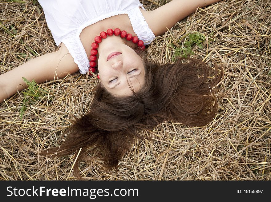 Beautiful girl lying at hay field.