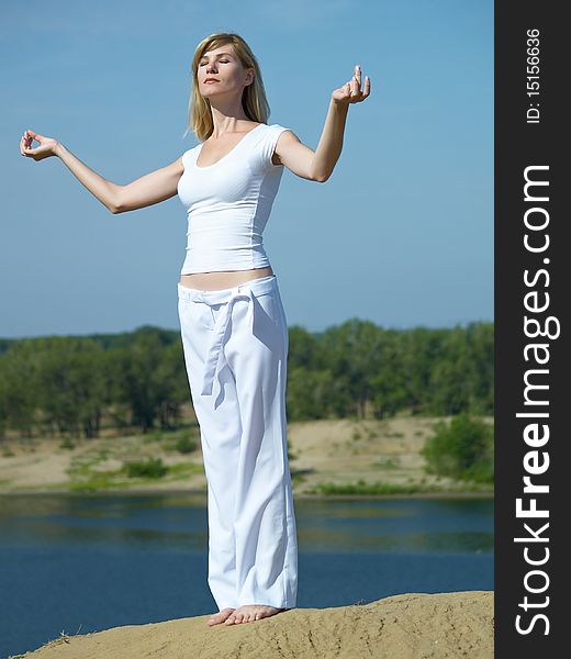 The girl in meditation on a background of the dark blue sky in the summer. The girl in meditation on a background of the dark blue sky in the summer