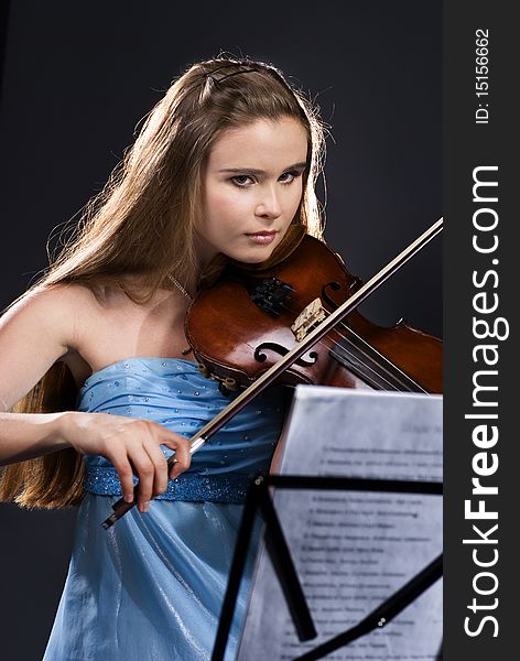 Pretty teenage girl/young woman playing violin on black background