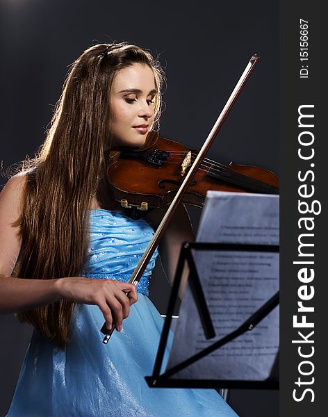 Pretty teenage girl/young woman playing violin on black background