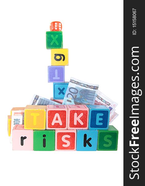 Assorted childrens toy letter building blocks against a white background that spell take risks. Assorted childrens toy letter building blocks against a white background that spell take risks