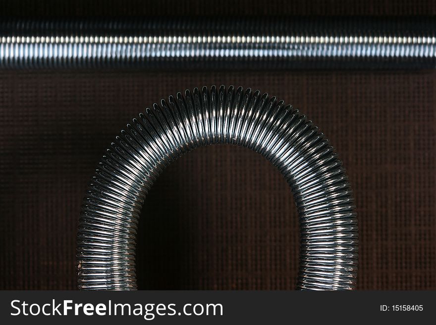 Metal spring deformed on an arch on a brown background.