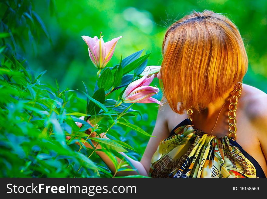 Red-haired girl and beautiful lily in the garden