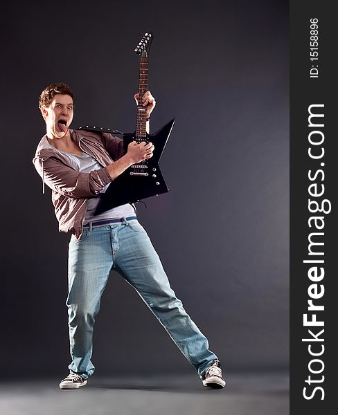 Picture of a passionate guitarist playing an electric guitar and sticking the tongue out