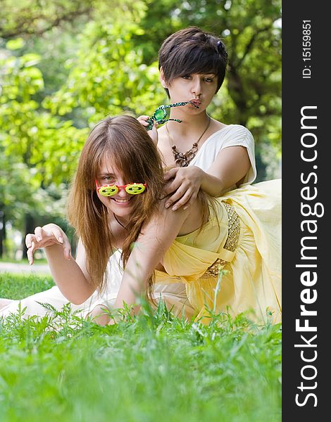 Two attractive young girls in funny sunglasses posing in green park area. Two attractive young girls in funny sunglasses posing in green park area