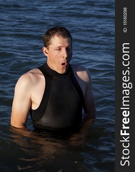 A man wearing his wet suit showing the expression of how cold the water is. A man wearing his wet suit showing the expression of how cold the water is.
