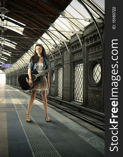 Young woman with guitar on a rail station platform. Young woman with guitar on a rail station platform