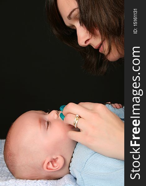 Brunette mother consoling her baby with a dummy. Brunette mother consoling her baby with a dummy