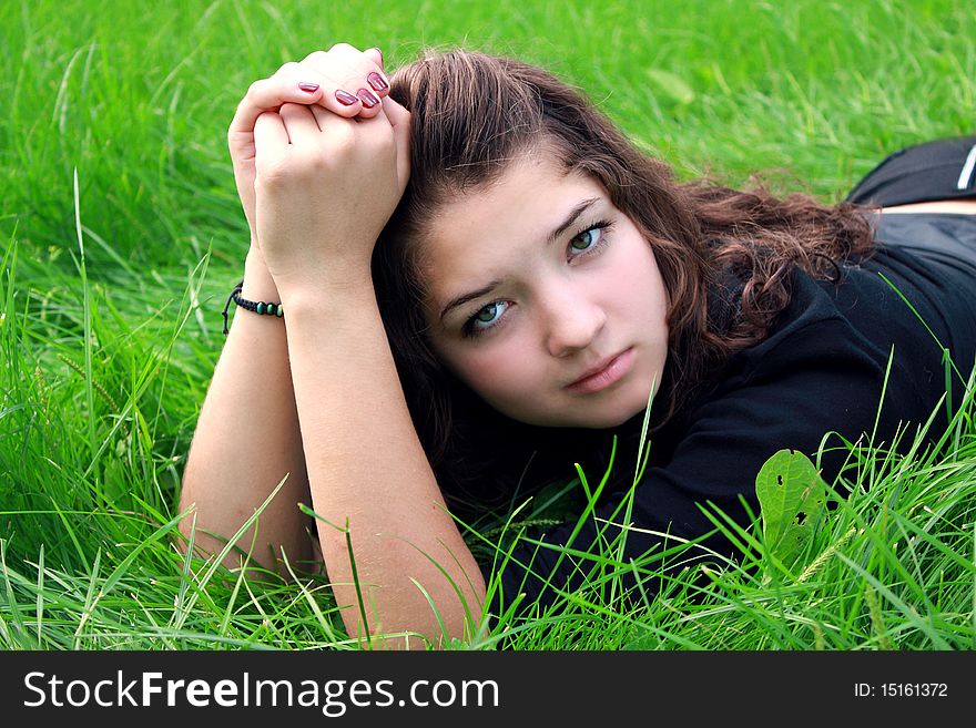 Girl the teenager lies on a green grass. Girl the teenager lies on a green grass.