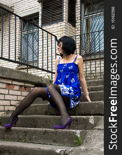 Girl in the blue dress is sitting on the stairs. Girl in the blue dress is sitting on the stairs