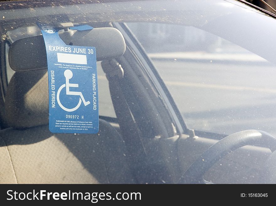 Handicap sign on a rear view mirror, in a muddy car.