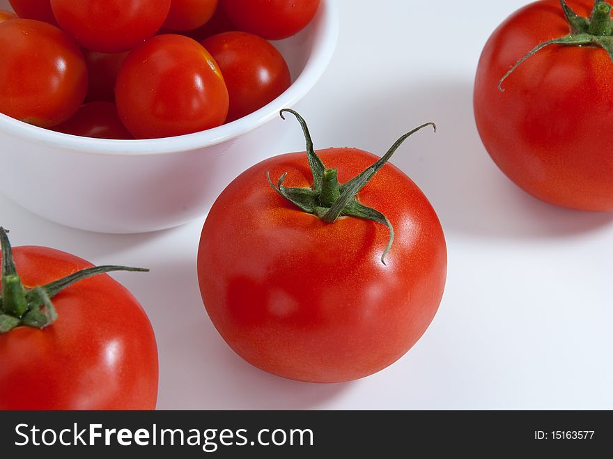 Close up of tomatoes and cherry tomatoes in a white background