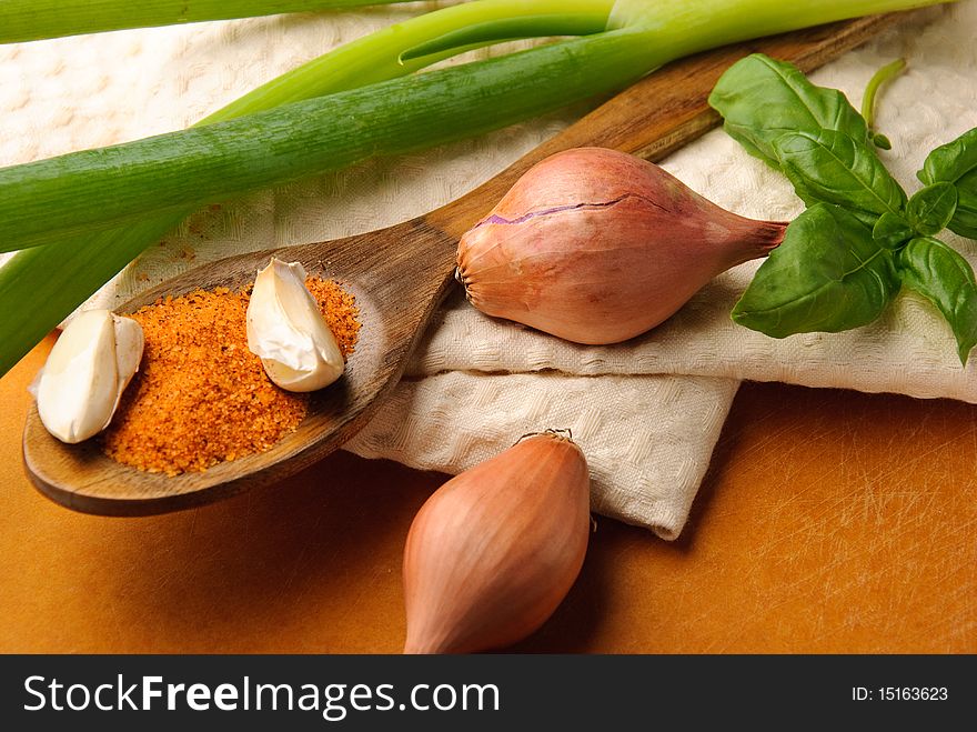 Spices on wooden spoon with green onions and basil leaves on a tea towel. Spices on wooden spoon with green onions and basil leaves on a tea towel