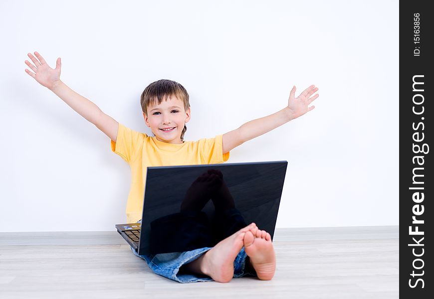 Happy little boy with laptop with moving apart his hands - indoors. Happy little boy with laptop with moving apart his hands - indoors