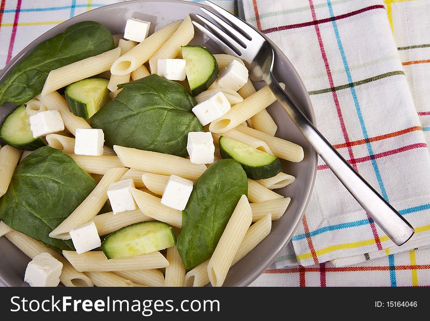 Penne pasta salad with spinach, cucumber and feta cheese.