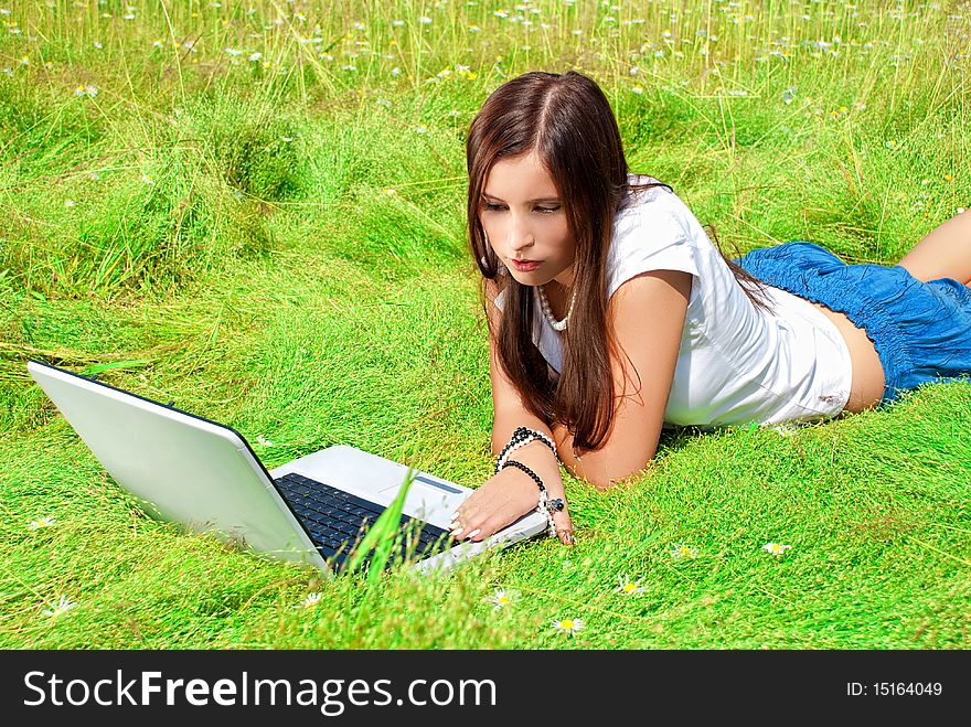 Beauty with computer on a grass.