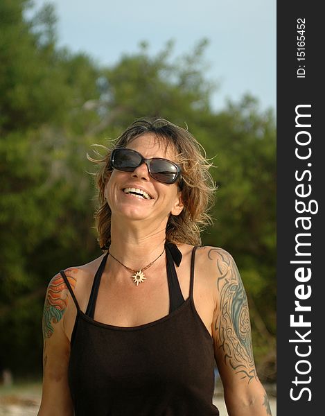 Happy smiling woman on beach with sunglasses and tattoos. Happy smiling woman on beach with sunglasses and tattoos.