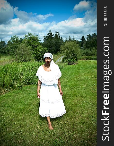 Beautiful black woman wearing scarf on head walking in grass. Beautiful black woman wearing scarf on head walking in grass