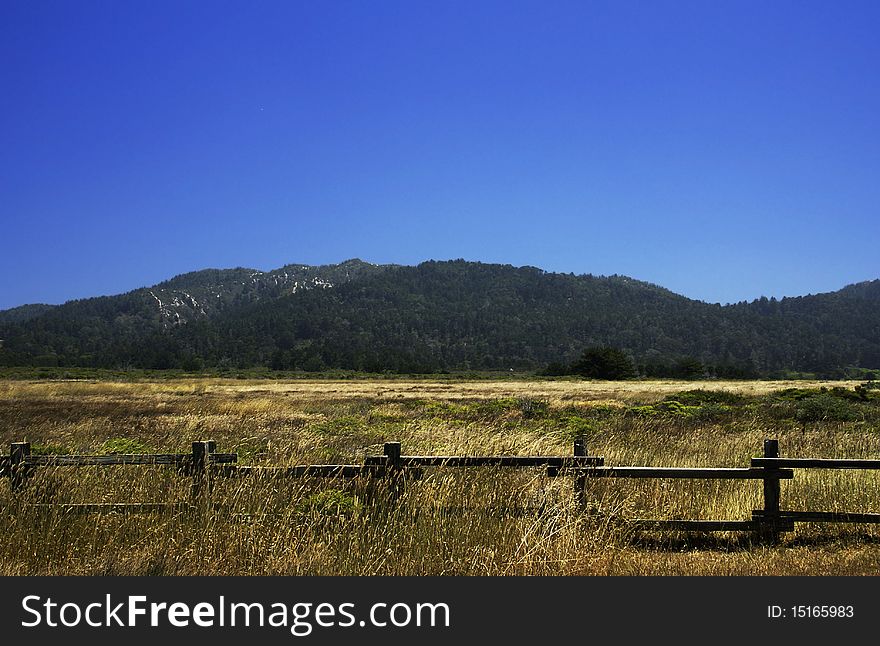 Landscape of a California field with mountains in the background and fence in the foreground. Landscape of a California field with mountains in the background and fence in the foreground