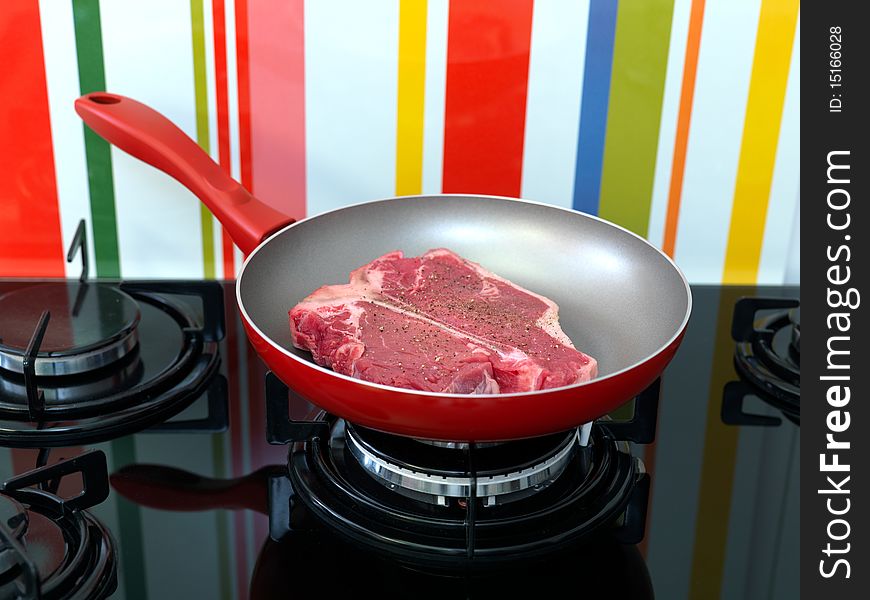 A T Bone steak in a frying pan on a stove top. A T Bone steak in a frying pan on a stove top