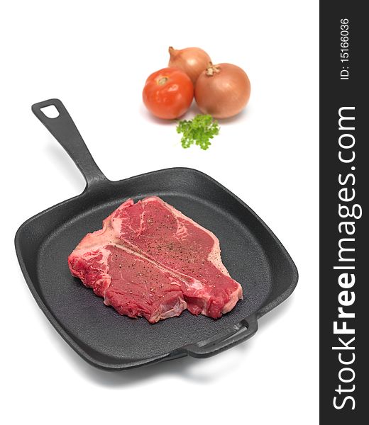 A T Bone steak in a frying pan isolated against a white background. A T Bone steak in a frying pan isolated against a white background