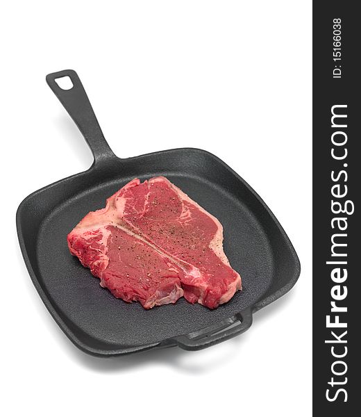 A T Bone steak in a frying pan  isolated against a white background. A T Bone steak in a frying pan  isolated against a white background