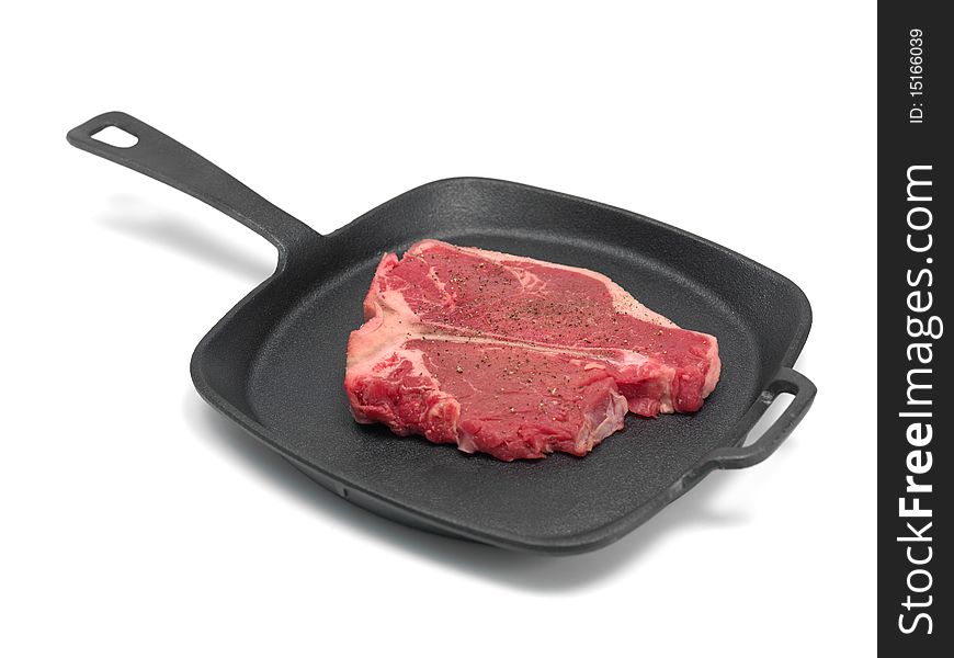 A T Bone steak in a frying pan isolated against a white background. A T Bone steak in a frying pan isolated against a white background