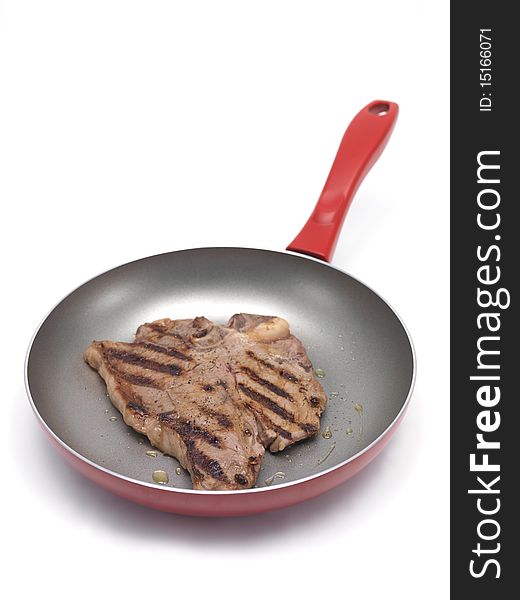 A T Bone steak in a frying pan  isolated against a white background