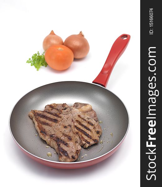 A T Bone steak in a frying pan isolated against a white background