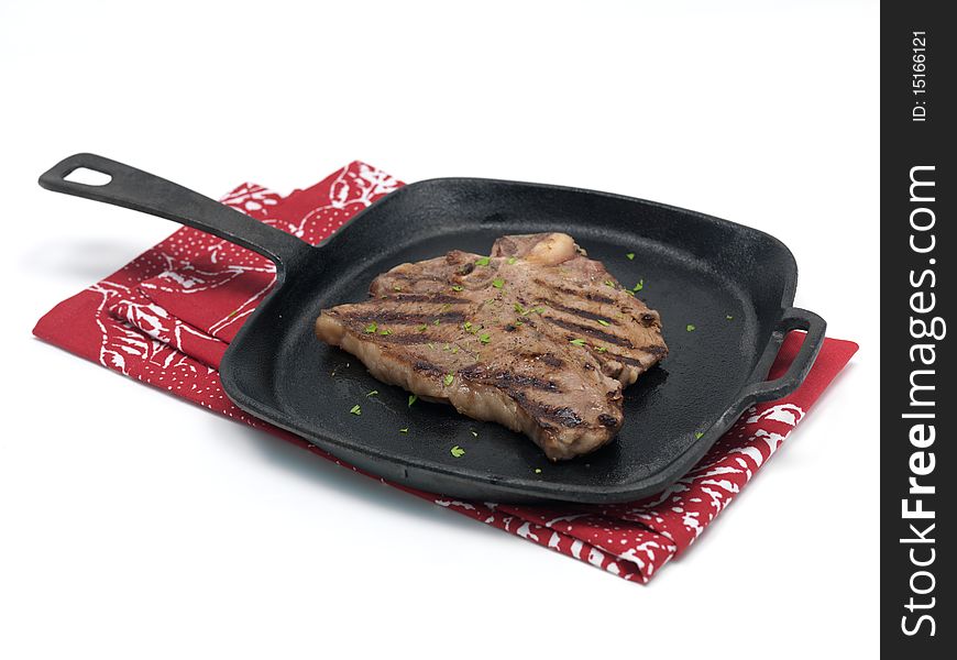 A T Bone steak in a frying pan isolated against a white background