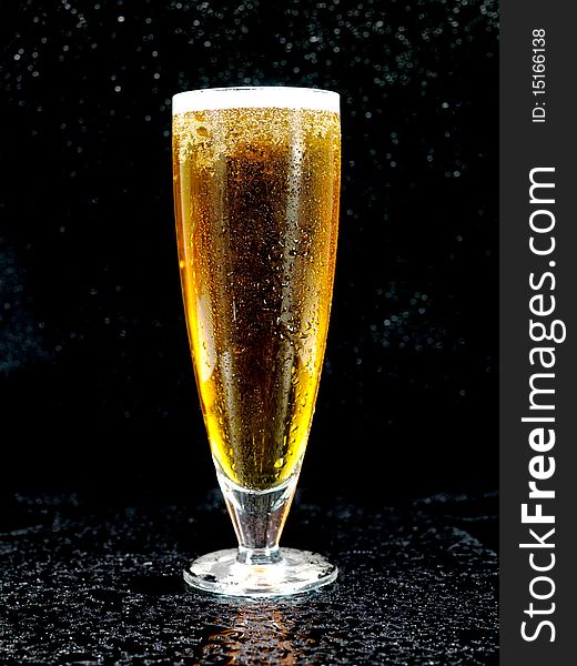 A glass of beer isolated against a black background. A glass of beer isolated against a black background