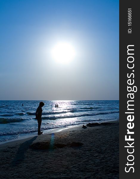 Beautiful sunset on the sea with the silhouettes of people walking on the beach