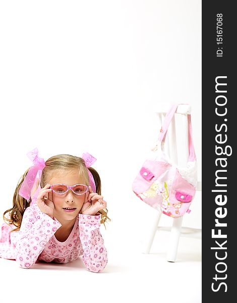 Young pretty blond girl with sunglasses, laying on the floor next to a white chair and pink hand bag. Young pretty blond girl with sunglasses, laying on the floor next to a white chair and pink hand bag