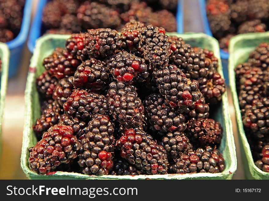 Blackberries in baskets in a farmers' market sold in bunches