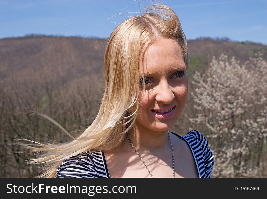 Blond girl posing in nature with hills and sky in background