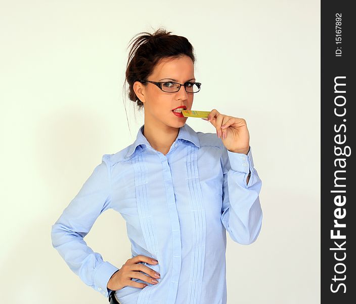 Girl wearing eyeglasses is holding credit card in her mouth. Girl wearing eyeglasses is holding credit card in her mouth