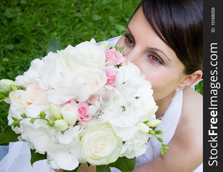 Happy bride with bouquet posing outdoors