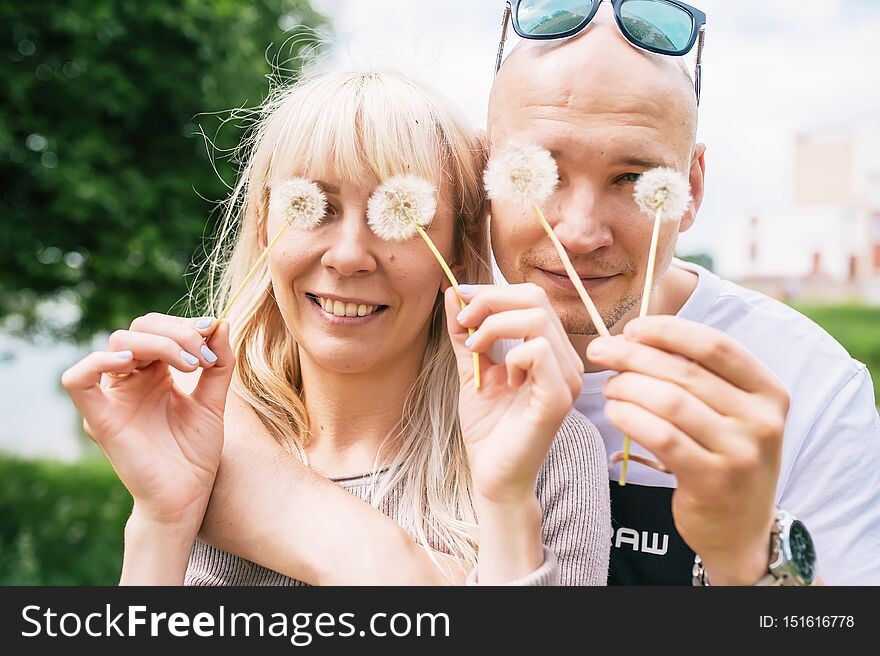 Loving Couple Smiling, Dandelions On Eyes As Eyeglasses. Joyful, Funny Spring,summer Day, Outdoors