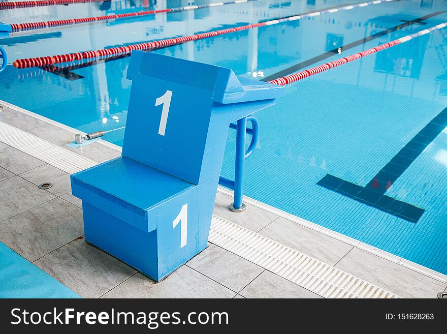 Starting block, number 1, swimming pool with an empty race track. Sport swimming.