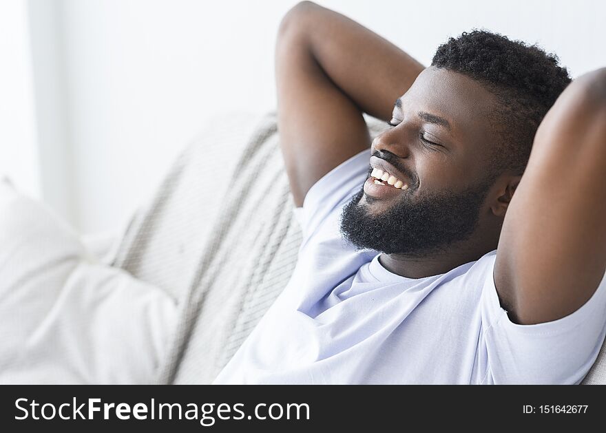 Free time. Happy african man enjoying weekend, relaxing at home, empty space