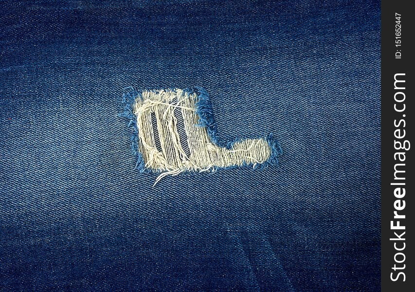 fragment of blue jeans fabric with a hole, full frame , close up
