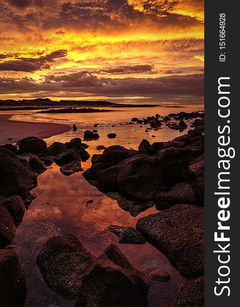 Beautiful reds, oranges and yellows colors of dawn light up the sky for a short time.  Rocks in the foreground and reflections in the water. Beautiful reds, oranges and yellows colors of dawn light up the sky for a short time.  Rocks in the foreground and reflections in the water.