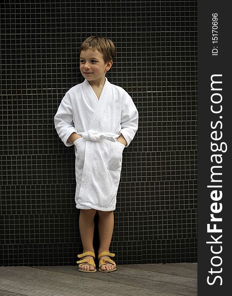 Cute little boy at spa wearing bathrobe