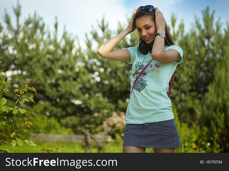 Young beautiful girl with earphones walking. Outdoor photo.